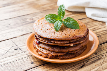Chocolate pancakes with berry jam and mint for Breakfast on wooden background