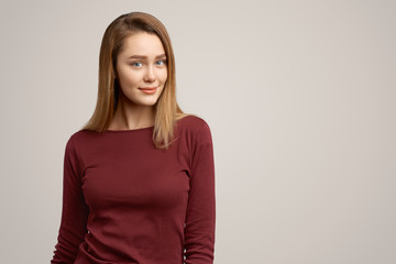 Obraz premium Photo of satisfied adorable young woman, smiles pleasantly at camera, rejoices coming holidays, isolated over white concrete wall. Positive human emotions