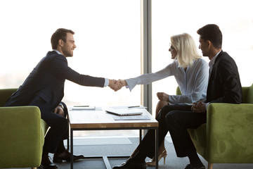 Happy middle aged businesswoman handshaking smiling businessman welcoming new partner at meeting, friendly female and male business people shaking hands, respect introduction, gender equality concept