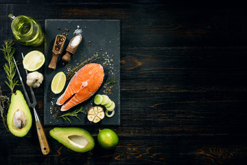salmon steak prepared for frying with ingredients on a dark background