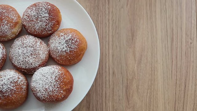 Homemade donuts on a round white plate. Revolves. View from above. On a wooden background.