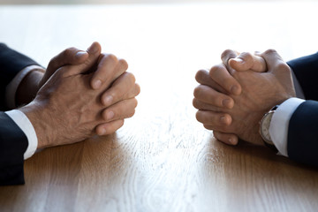 Clasped hands of two business men negotiators opponents opposite on table as politicians dialogue...