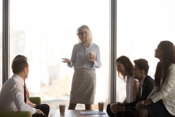 Happy mature ceo coach mentor leader talking to diverse team employees chatting at business...