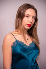 Half-length portrait of blonde girl in blue satin tank top with lace. Perfect makeup with red lips. White background. Copy space.