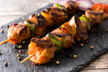 Chicken shish kebab with vegetables on wooden table