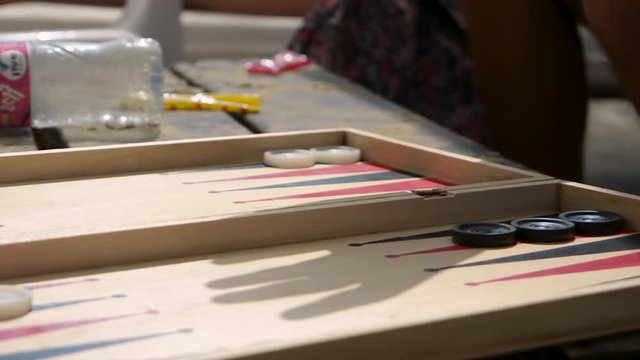 Closeup of a man carefully moving backgammon peaces on a board, during a backgammon game in the beach.