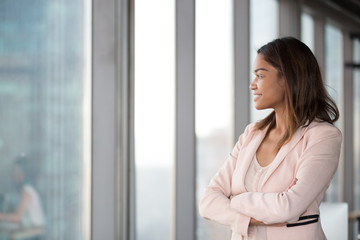 Smiling confident african millennial businesswoman looking at window think about future hope for new opportunities, thoughtful black female executive dream enjoy success, business vision concept