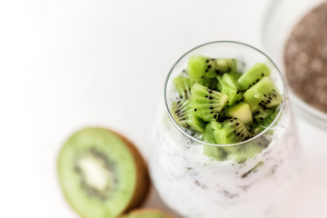 Naklejka na ściany i meble pudding of kefir Chia and kiwi seeds in a glass on a light background horizontally.Portion of natural yogurt with chia seed and kiwi slices in a jar for a breakfast.copy spase