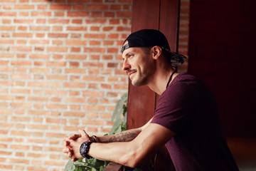 Side portrait of smiling confident handsome male artist, wearing trendy outfit, keeping elbows on...