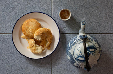 Chinese pastry in white dish with Chinese tea and teapot on dark wooden background which has dim...