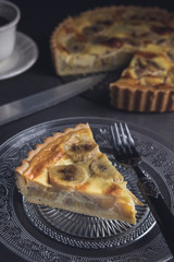 Sliced homemade banana custard tart served in a plate. Vertical