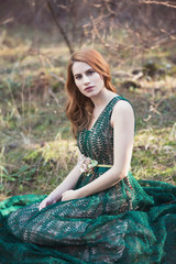 beautiful young redhead woman in green dress in the forest