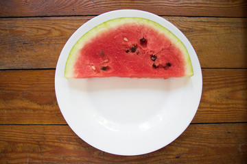 Pieces of watermelon in bowl and slice on white plate. Top view