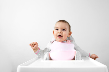 Happy baby boy in high chair with spoon in his hand