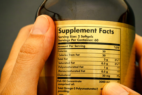 Glass Jar With Supplement Facts In Woman Hands. Close-up.