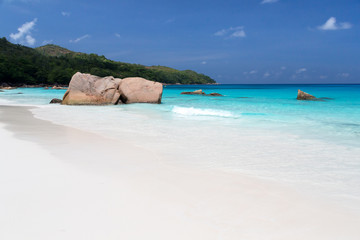 Beach with blue water and blue sky and some rocks