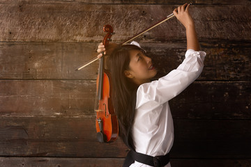 Naklejka premium Beautiful woman stand ,hold violin,play music on wooden background, in emotion feeling committed.