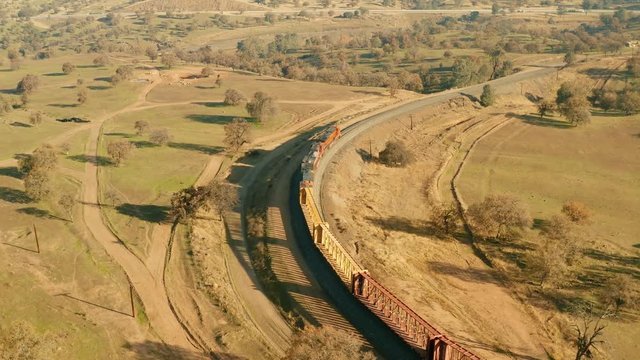 The powerful locomotives charge from the west end of the tunnel. The aerial camera follows them slightly behind the locomotives. The train enters the trench that 3000 Chinese laborers dug by hand.