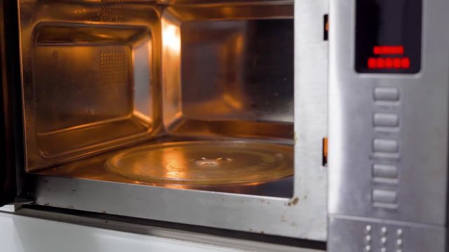 Woman hand cleaning a microwave oven with a cloth and spray. Shot in 4k resolution