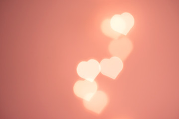 Beautiful pattern from flying bokeh sparkling garland lights in heart shape on pastel pinkish...