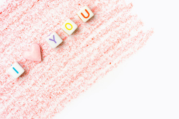 Phrase I Love You constructed from white letter cubes and pink heart shape sugar candy on red pencil strokes background on white paper. Romance Valentine Mother's Day. Greeting Card Poster Banner