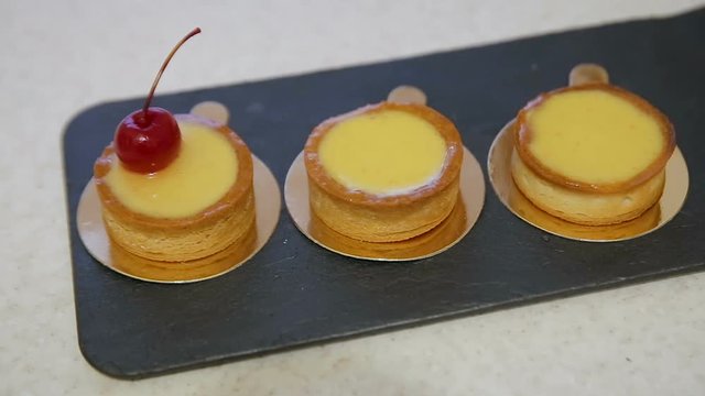 Bakery chef put cherry fruit decorate on cake cream. Concept Bakery chef, Making cake, bakery business