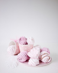 Pink and white meringues on white background