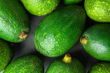 Heap of ripe raw avocados on dark stone background. Top view. Copy space. Healthy lifestyle vitamins oil mediterranean cuisine balanced diet concept. Poster banner template