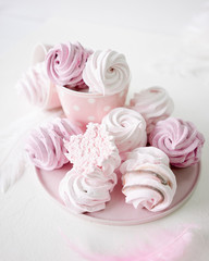 White and pink meringues on white background. Pink plate and cup on polka dot
