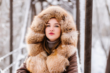 Beautiful girl in fur on a winter background posing on camera, enjoying life, laughing, beautiful...