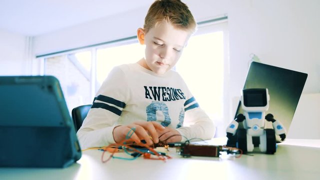 Kid plays with a mini computer connected to his laptop computer