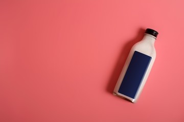 Glass bottle with white liquid (milk, cream, sauce) isolated on colour background