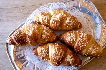 Freshly baked croissants with marzipan on plate, wooden background, cafe, bakery.