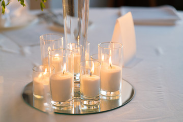 candles stand in the center of a round table in a restaurant