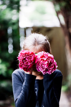 Young girl hading her face with flowers