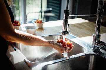 Woman washing fruits ta home in summer
