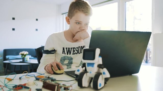 Kid uses a laptop computer and looks concentrated at the screen