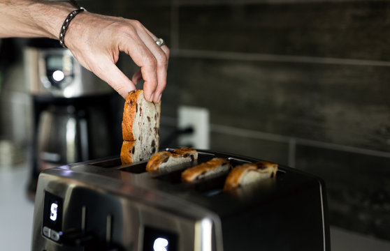 Male hand taking baked toast out of toaster