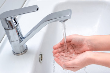 Washing of girl's hands with soap under the crane with water