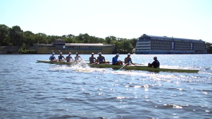 Rowing team summer training. 8 athletes rowers in a boat in the river Dnipro. City area in Kiev, Ukraine