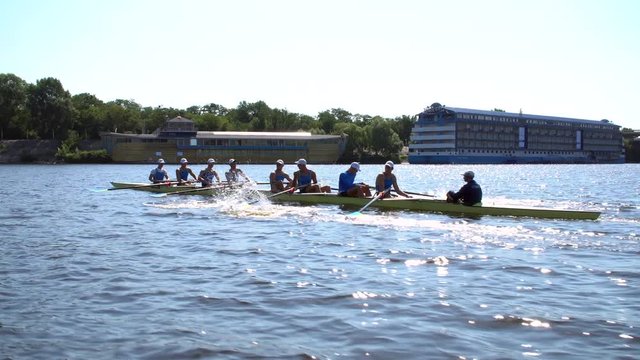 Rowing team summer training. 8 athletes rowers in a boat in the river Dnipro. City area in Kiev, Ukraine