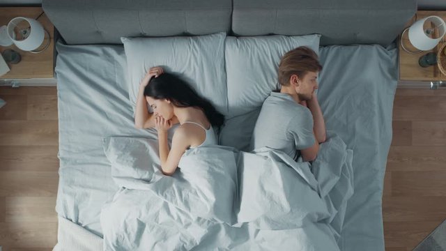 Quarrelling Young Couple in the Bed, Young People in a Row Turn Away From Each other and Lay on Their Sides Holding Grudges and Being Offended 