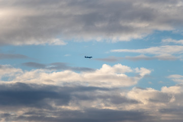 Kleines Flugzeug im weiten Himmel zwischen den Wolken durch