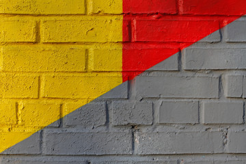 Colorful (yellow, grey and red) brick wall as background, texture