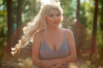 Young beautiful blonde woman in blue sexy dress - neglegee pegnoir underwear posing in forest in summer