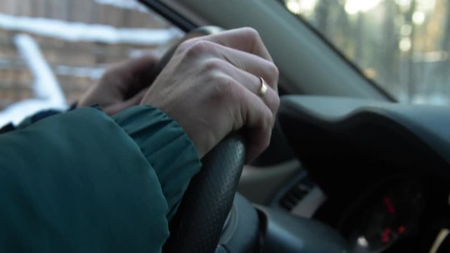 In winter men's hands rotate the steering wheel in car, close up