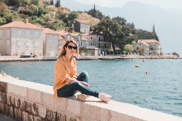 life style. travel and freedom. A girl in the background of the mountains of Montenegro sits in the old town by the sea.