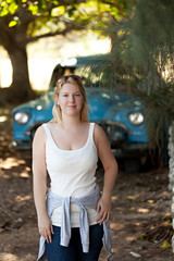 Young blonde woman staying in front of blue old retro car in Cuba