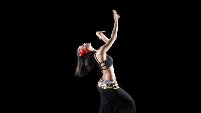 Pretty young woman dancing zumba while wearing sportswear in the studio. Shot in 4k resolution with dark background