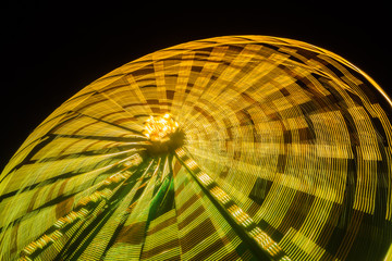 Ferris wheel in motion at the amusement park, night illumination. Long exposure